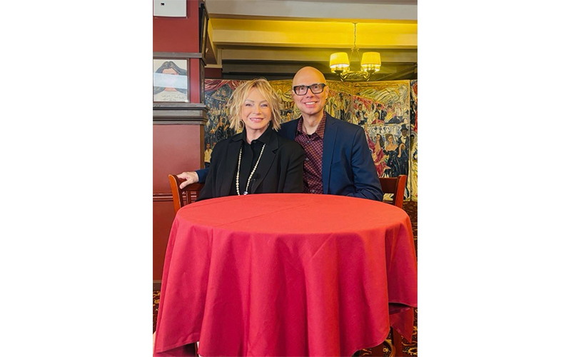 Judy Craymer sitting on a table with a red table cloth. 